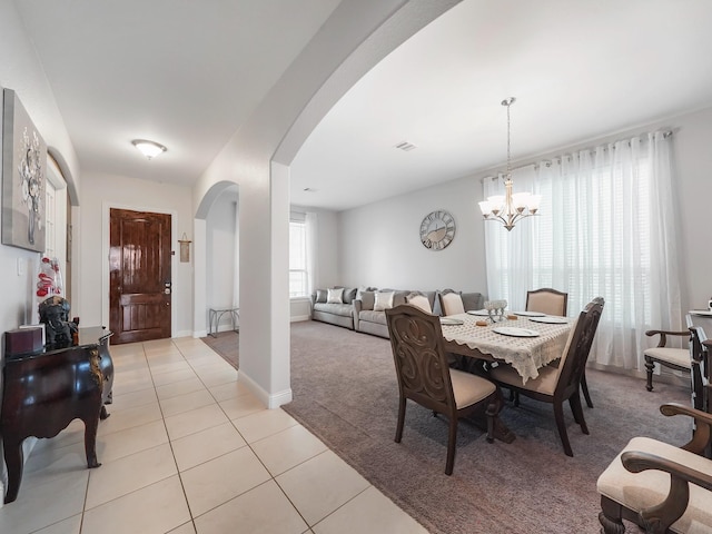 dining room featuring light tile patterned floors, visible vents, arched walkways, light colored carpet, and a chandelier