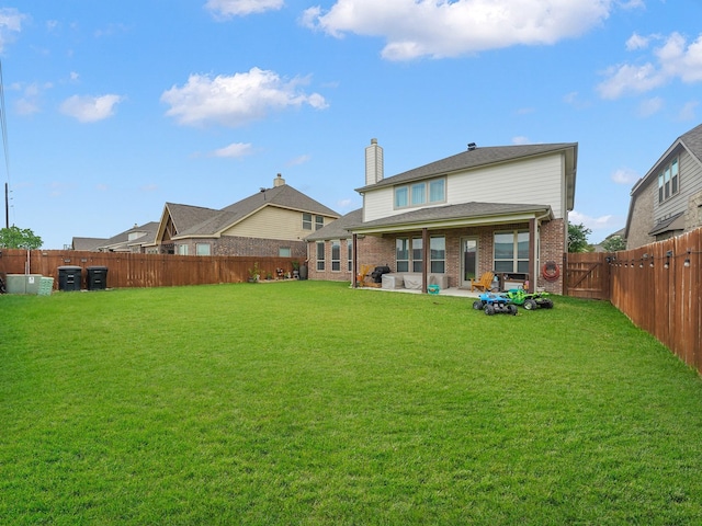 back of property featuring a lawn, brick siding, and a fenced backyard
