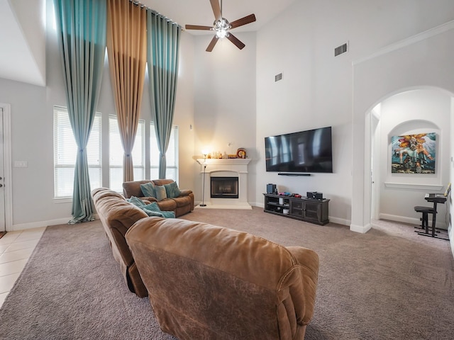 living area featuring a ceiling fan, high vaulted ceiling, visible vents, arched walkways, and light carpet