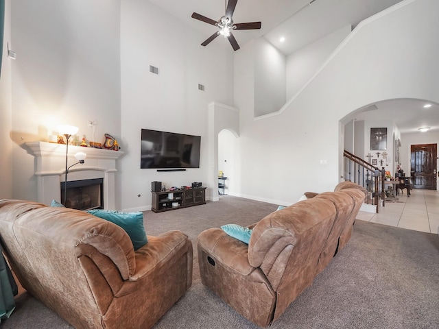 living room featuring high vaulted ceiling, carpet floors, baseboards, ceiling fan, and arched walkways