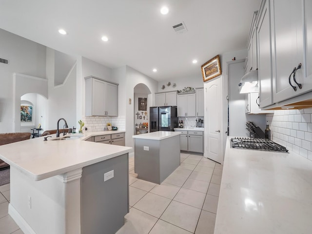 kitchen featuring arched walkways, stainless steel appliances, decorative backsplash, and a sink