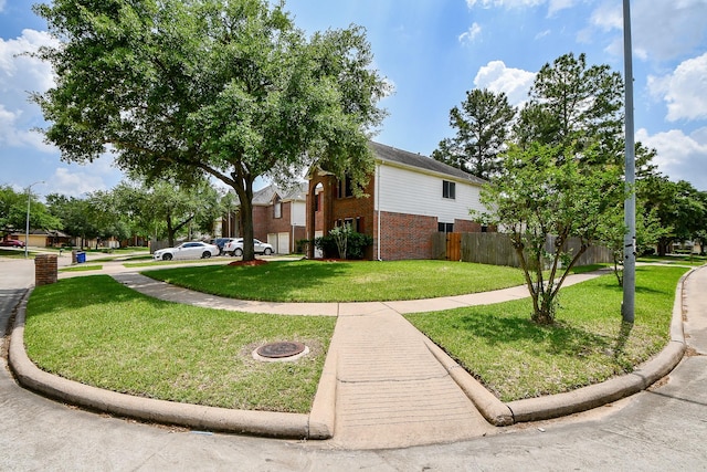 view of home's exterior featuring brick siding, fence, and a lawn