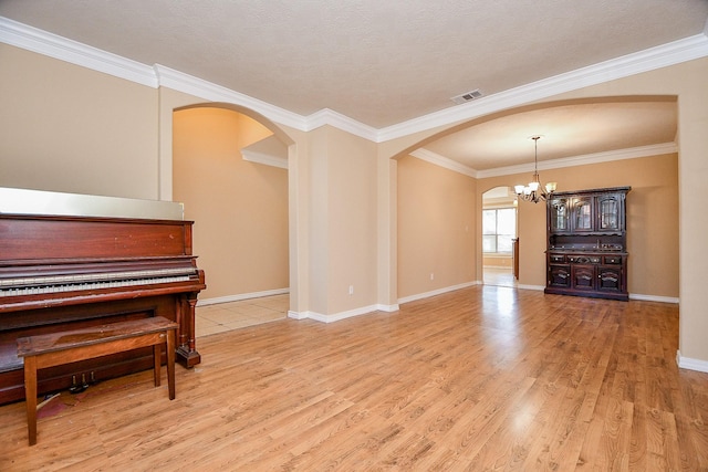 living room featuring visible vents, an inviting chandelier, light wood-style flooring, crown molding, and arched walkways
