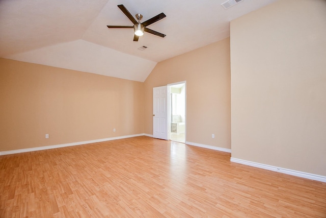 empty room with light wood-style floors, visible vents, lofted ceiling, and ceiling fan