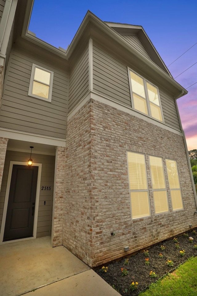 property exterior at dusk featuring brick siding