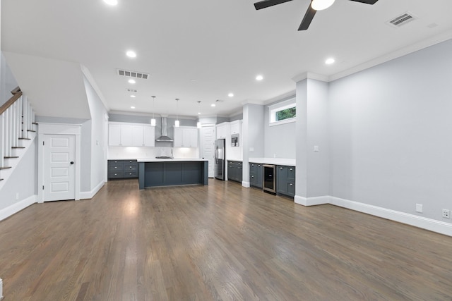 unfurnished living room with stairway, wine cooler, ceiling fan, and visible vents