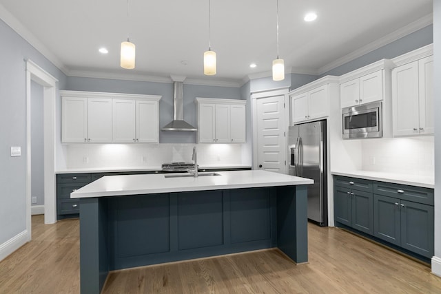 kitchen featuring a sink, stainless steel appliances, light countertops, and wall chimney range hood
