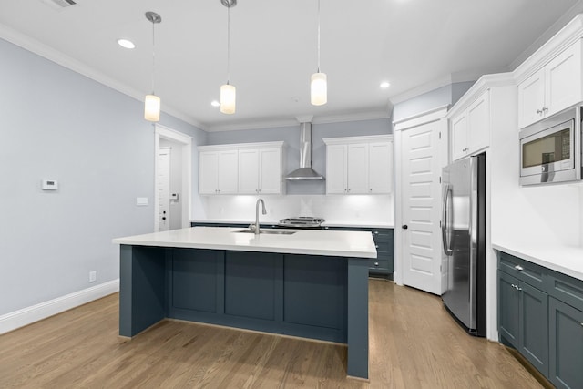 kitchen featuring stainless steel appliances, a sink, wall chimney exhaust hood, light countertops, and white cabinets