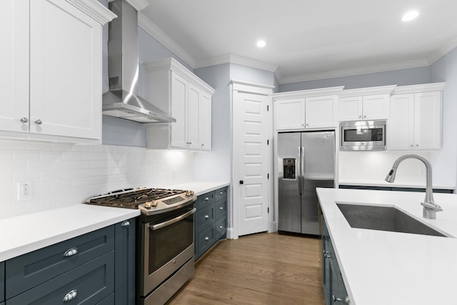 kitchen with a sink, stainless steel appliances, wall chimney exhaust hood, light countertops, and white cabinets