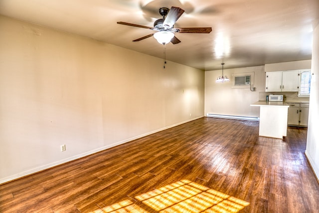 401 E Main St, Brenham, TX 77833 - unfurnished living room featuring a baseboard heating unit, dark wood finished floors, a ceiling fan, baseboards, and an AC wall unit