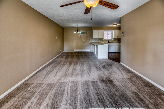 401 E Main St, Brenham, TX 77833 - unfurnished living room with baseboards, a sink, a wall mounted air conditioner, ceiling fan, and carpet