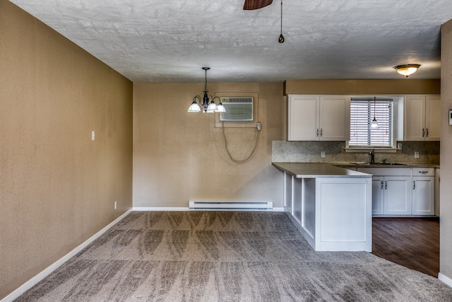 401 E Main St, Brenham, TX 77833 - kitchen featuring baseboard heating, white cabinetry, a sink, dark carpet, and a chandelier