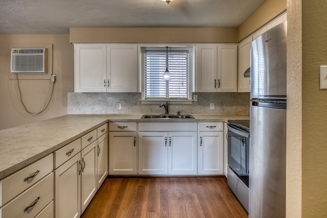 401 E Main St, Brenham, TX 77833 - kitchen featuring a sink, appliances with stainless steel finishes, a wall unit AC, dark wood-type flooring, and light countertops