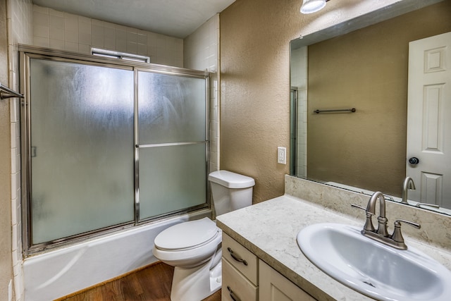 401 E Main St, Brenham, TX 77833 - bathroom with a textured wall, wood finished floors, enclosed tub / shower combo, toilet, and vanity