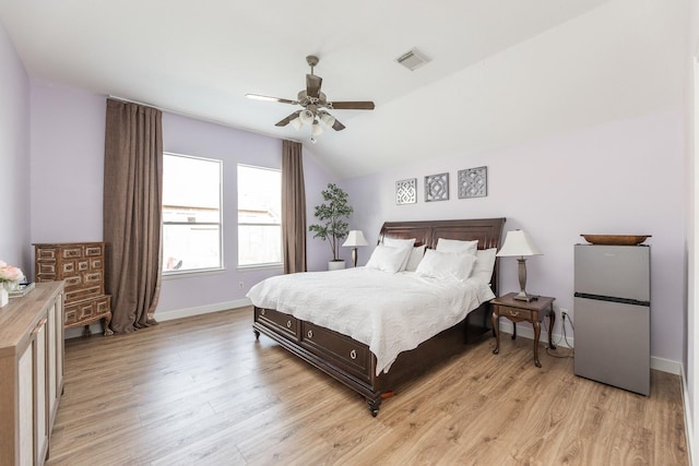 bedroom with freestanding refrigerator, light wood-style floors, visible vents, and lofted ceiling