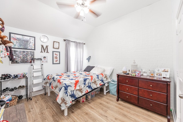 bedroom with brick wall, lofted ceiling, a ceiling fan, and wood finished floors