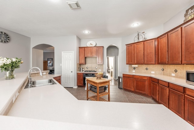 kitchen with arched walkways, appliances with stainless steel finishes, visible vents, and a sink