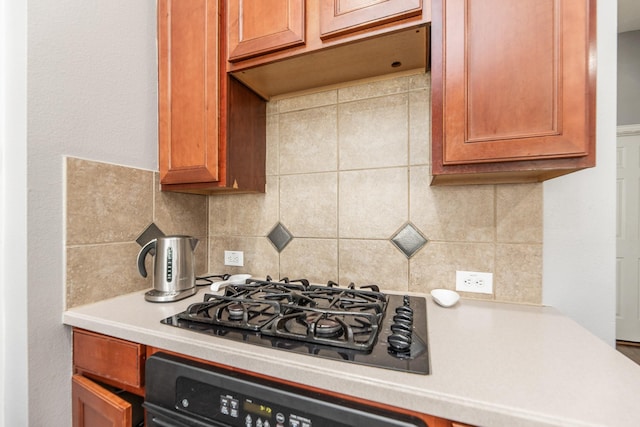 kitchen featuring light countertops, oven, decorative backsplash, and black gas cooktop