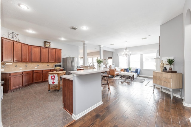 kitchen with visible vents, open floor plan, a kitchen breakfast bar, light countertops, and appliances with stainless steel finishes