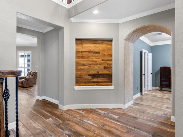 hall featuring arched walkways, ornamental molding, wood-type flooring, and baseboards