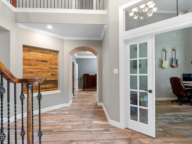 entrance foyer with crown molding, arched walkways, french doors, and wood finished floors