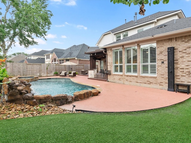 view of pool with a yard, fence, a patio, and a pool with connected hot tub