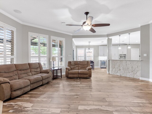 living area featuring ornamental molding, light wood-type flooring, and ceiling fan