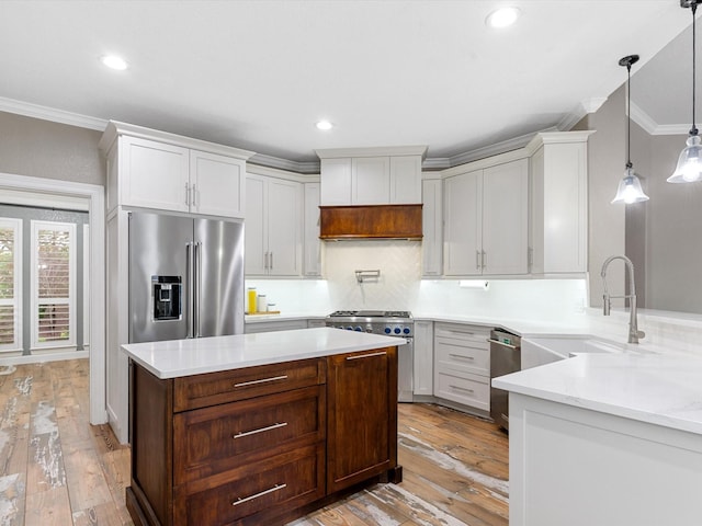 kitchen featuring crown molding, high quality appliances, decorative backsplash, and light wood-type flooring