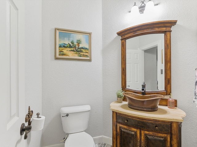 bathroom featuring toilet, baseboards, and vanity