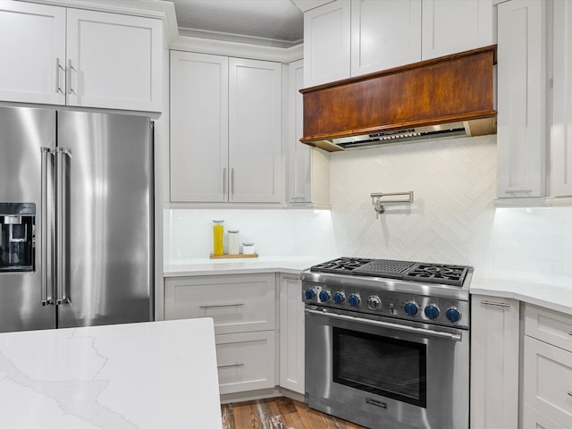 kitchen with white cabinets, high quality appliances, premium range hood, and backsplash