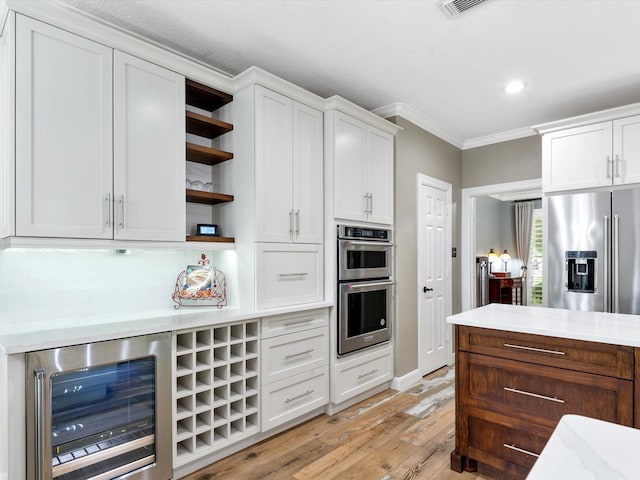 kitchen featuring appliances with stainless steel finishes, ornamental molding, open shelves, beverage cooler, and light wood-style floors