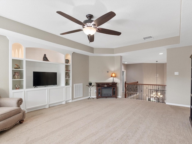 living room featuring carpet, visible vents, baseboards, and ceiling fan with notable chandelier