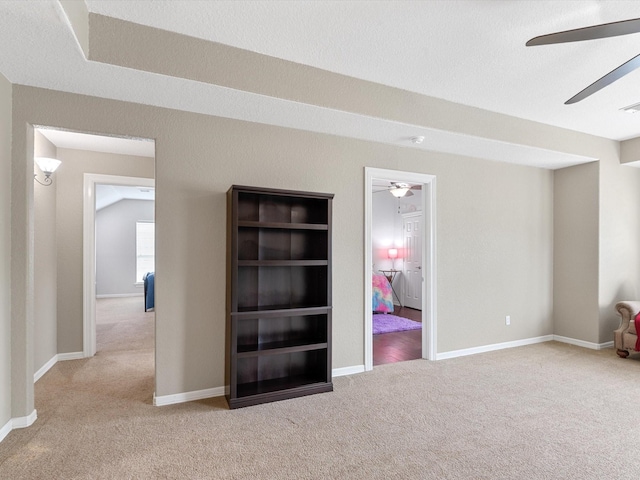 carpeted empty room with a ceiling fan, baseboards, and visible vents
