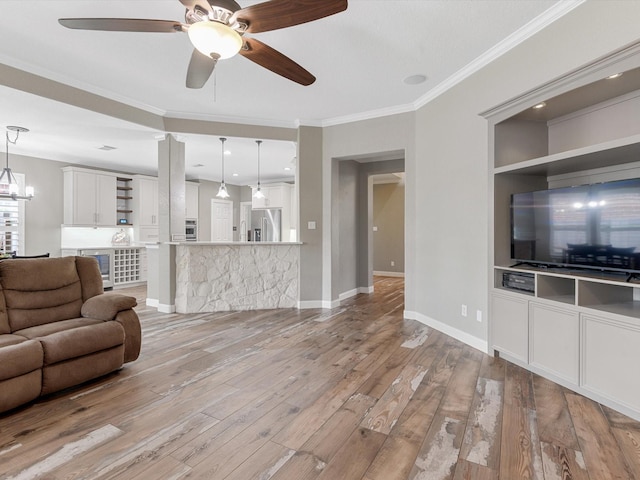 living room with light wood finished floors, ornamental molding, baseboards, and a ceiling fan