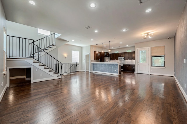 2424 Hadley St, Houston, TX 77003 - unfurnished living room featuring baseboards, dark wood-style flooring, stairway, and plenty of natural light