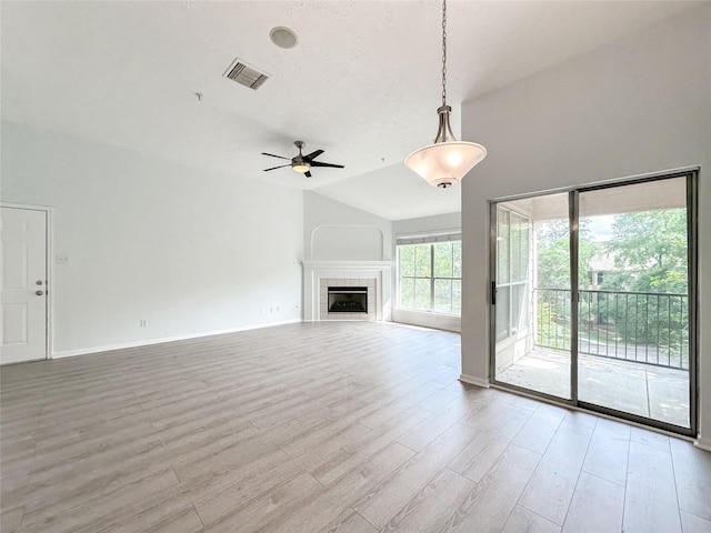 8051 Bay Branch Dr Unit 131, The Woodlands, TX 77382 - unfurnished living room with a ceiling fan, visible vents, vaulted ceiling, a fireplace, and wood finished floors