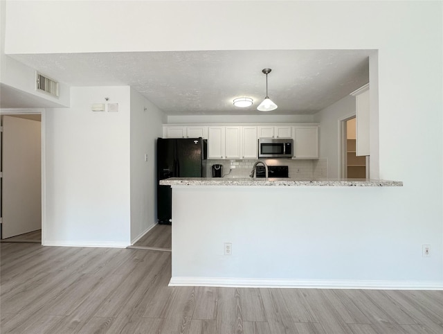 8051 Bay Branch Dr Unit 131, The Woodlands, TX 77382 - kitchen with freestanding refrigerator, light wood-style floors, visible vents, and stainless steel microwave