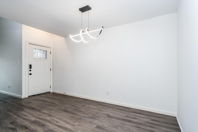 unfurnished dining area with baseboards and dark wood-style flooring