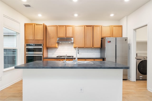 14627 Monterey Cypress Dr, Houston, TX 77068 - kitchen with washer / dryer, dark countertops, under cabinet range hood, and a sink