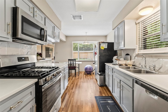 kitchen featuring a sink, stainless steel appliances, visible vents, backsplash, and light countertops