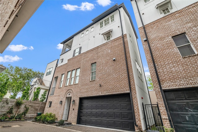 view of property featuring driveway, fence, and a garage