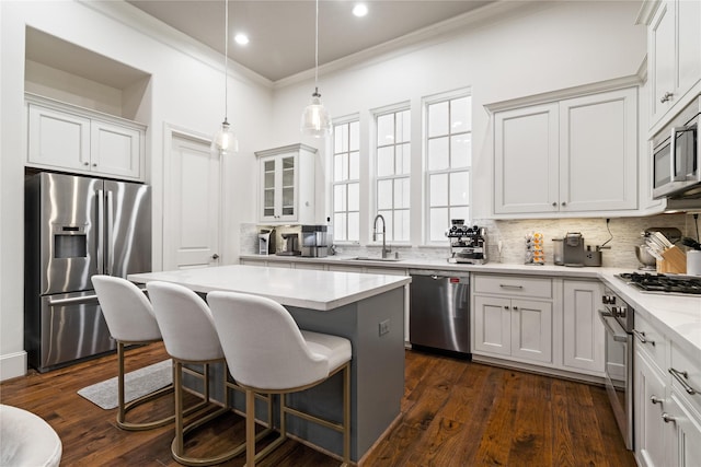 kitchen featuring a sink, stainless steel appliances, ornamental molding, a kitchen breakfast bar, and decorative backsplash