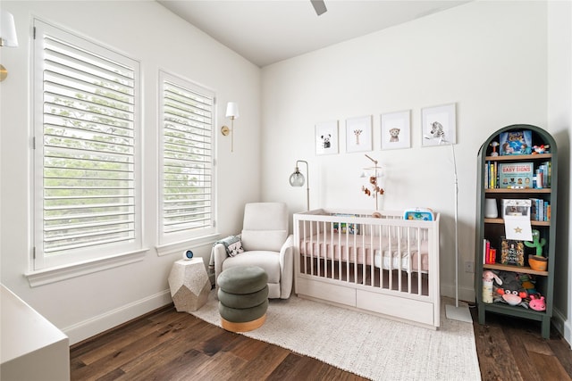 bedroom with multiple windows, a crib, and wood finished floors