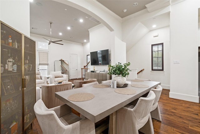 dining room featuring stairway, crown molding, arched walkways, and a ceiling fan