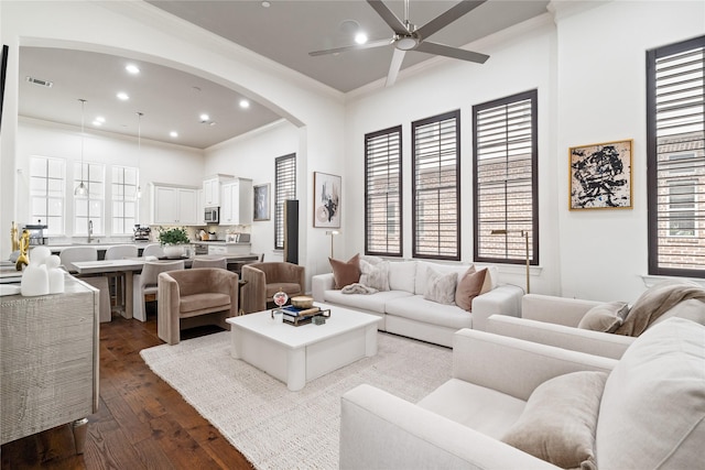 living room with recessed lighting, dark wood-style flooring, ceiling fan, crown molding, and arched walkways