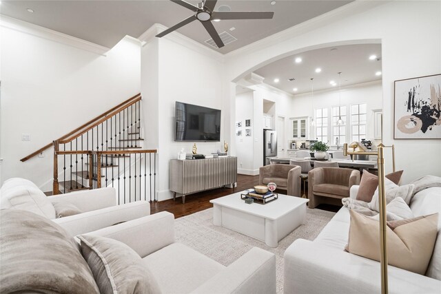 living room with a ceiling fan, dark wood-style flooring, arched walkways, ornamental molding, and recessed lighting