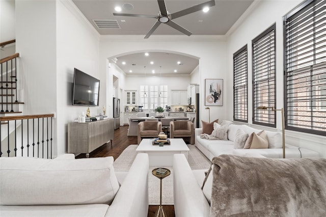 living area with a ceiling fan, ornamental molding, visible vents, dark wood-type flooring, and arched walkways