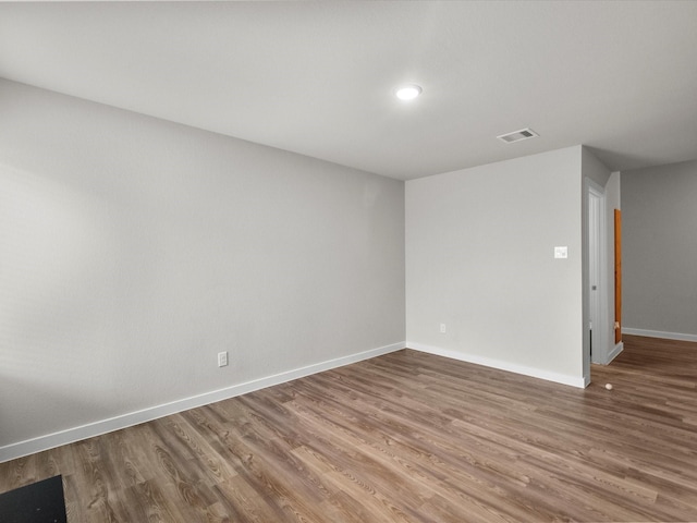 spare room with baseboards, visible vents, and wood finished floors