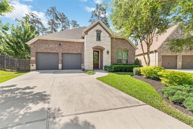 145 Lily Green Ct, Conroe, TX 77304 - french country style house featuring brick siding, concrete driveway, stone siding, and a garage