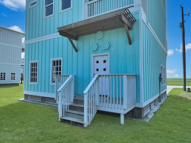 525 Annabelle Dr, Gilchrist, TX 77617 - view of exterior entry with board and batten siding, a deck, and a lawn